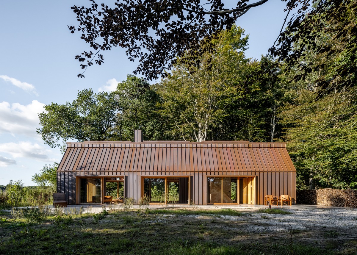 Медный дом творческого человека в лесу у озера в Дании